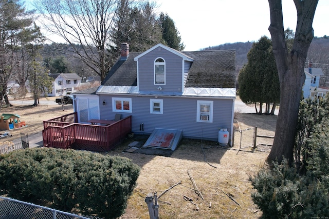 rear view of property with a shingled roof, a wooden deck, fence, and a chimney