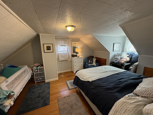 bedroom with baseboards, lofted ceiling, and wood finished floors