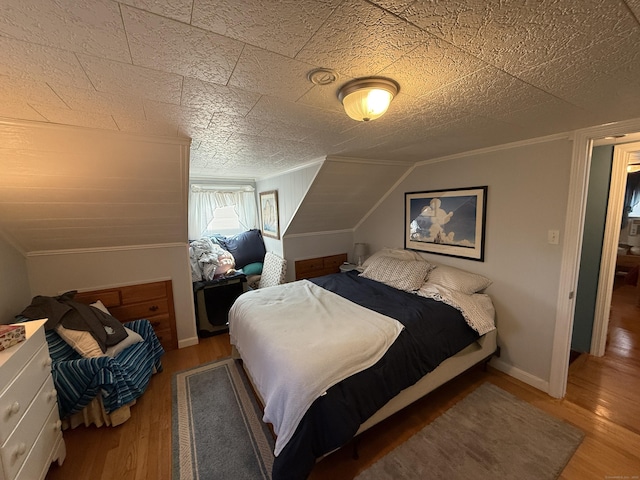 bedroom with crown molding, wood finished floors, baseboards, and lofted ceiling