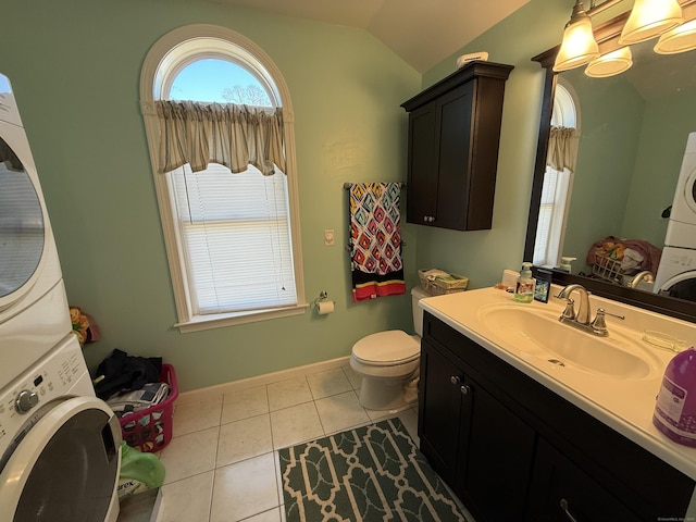 bathroom with tile patterned floors, toilet, stacked washer and clothes dryer, vanity, and vaulted ceiling