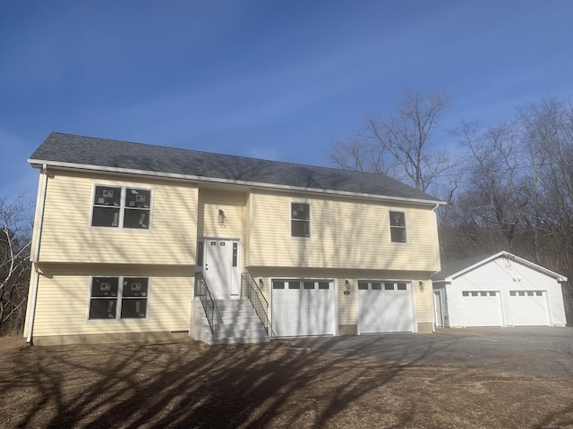 bi-level home with entry steps, an outdoor structure, a garage, and driveway