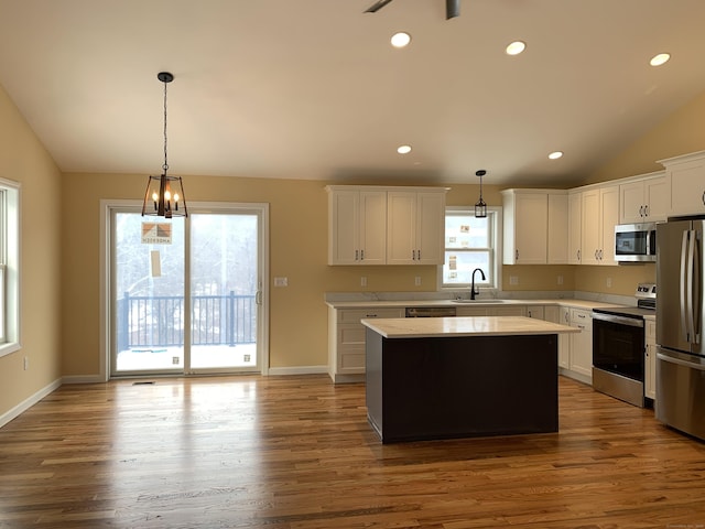 kitchen featuring a healthy amount of sunlight, vaulted ceiling, light countertops, appliances with stainless steel finishes, and white cabinetry