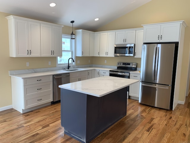 kitchen featuring vaulted ceiling, white cabinets, appliances with stainless steel finishes, and a sink