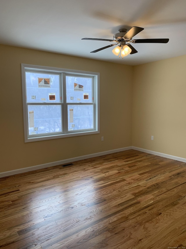 spare room with visible vents, a ceiling fan, baseboards, and wood finished floors