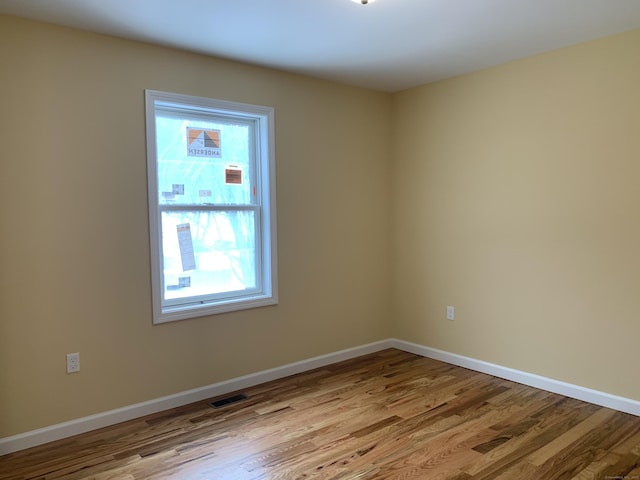 unfurnished room with visible vents, baseboards, and wood finished floors