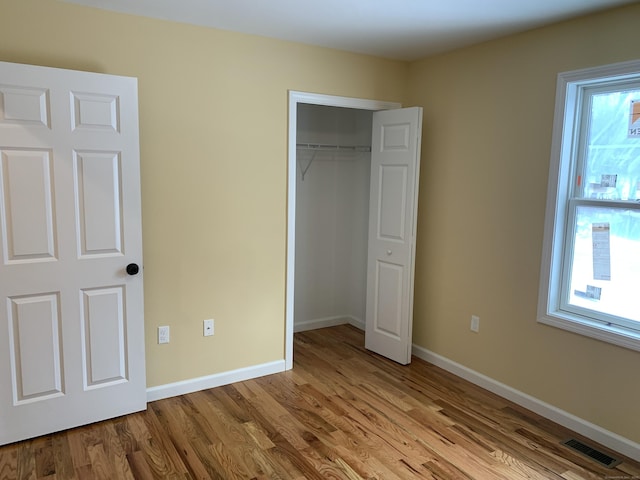 unfurnished bedroom with visible vents, baseboards, a closet, and wood finished floors