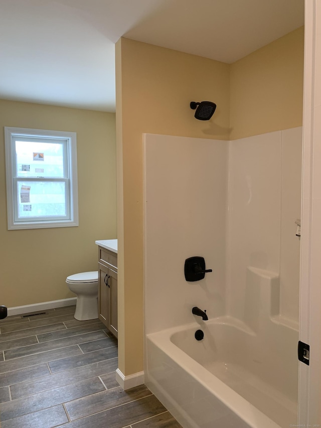 full bath with baseboards, wood tiled floor, toilet, shower / bathing tub combination, and vanity