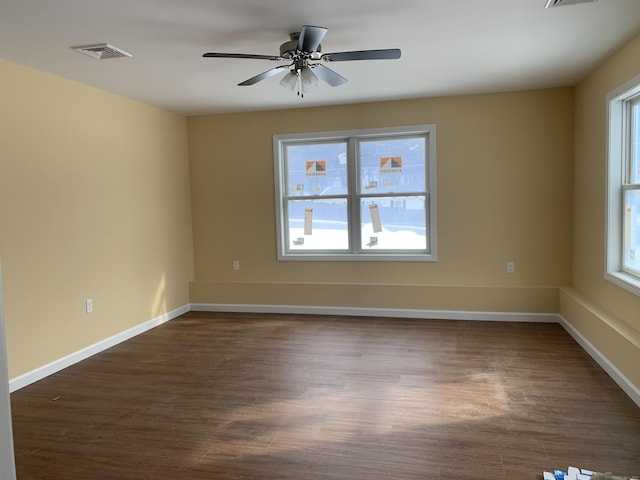 unfurnished room featuring visible vents, baseboards, dark wood finished floors, and a ceiling fan