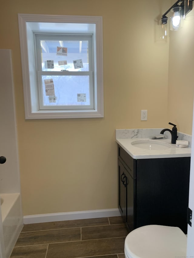 bathroom featuring wood tiled floor, baseboards, toilet, and vanity