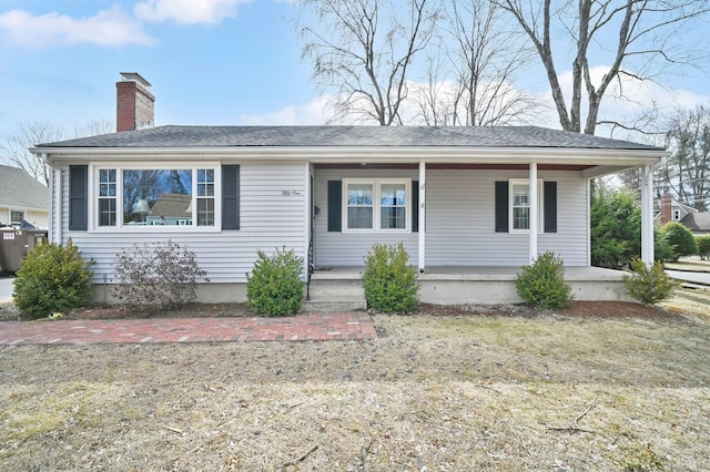 view of front of property with covered porch, a chimney, and a shingled roof