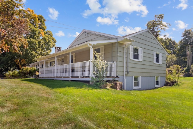 view of side of home with covered porch and a yard