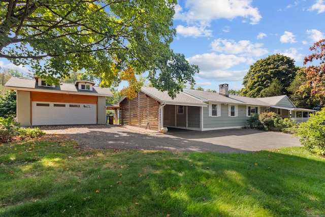 view of front of house with a detached garage, a chimney, and a front lawn