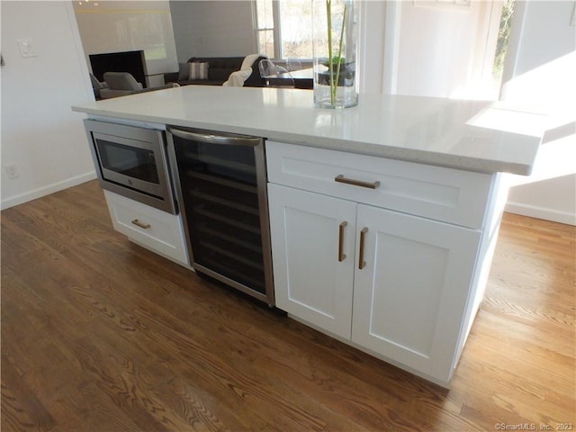 kitchen with stainless steel microwave, dark wood-style floors, open floor plan, white cabinetry, and wine cooler