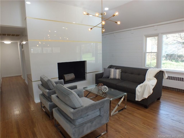 living area with a chandelier, visible vents, radiator heating unit, and wood finished floors