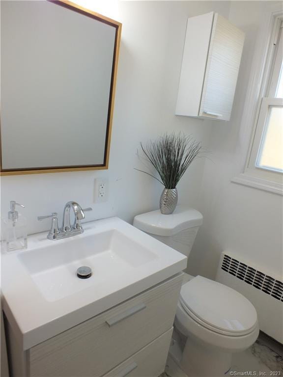 bathroom with toilet, radiator, vanity, and marble finish floor