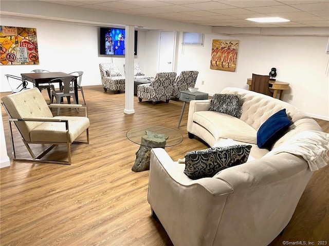 living room featuring wood finished floors, baseboards, and a drop ceiling