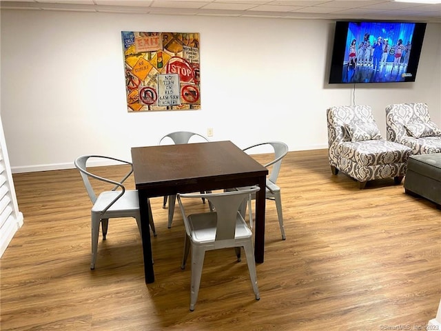 dining space featuring wood finished floors, baseboards, and a drop ceiling