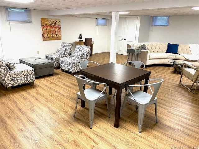 dining area with a drop ceiling and light wood-style flooring