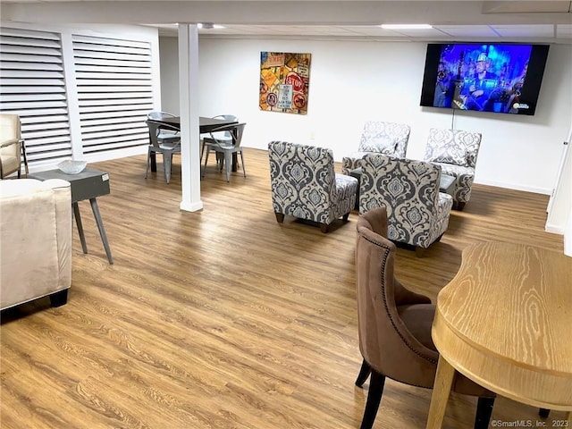 living room with a drop ceiling, baseboards, and wood finished floors