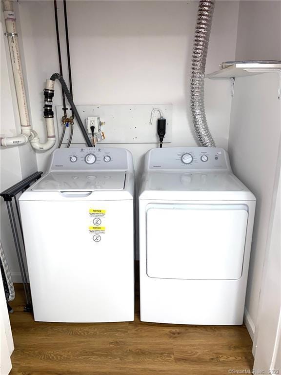 laundry room featuring wood finished floors, laundry area, and washer and clothes dryer