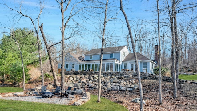 view of front of property with a front lawn, a fire pit, and a sunroom