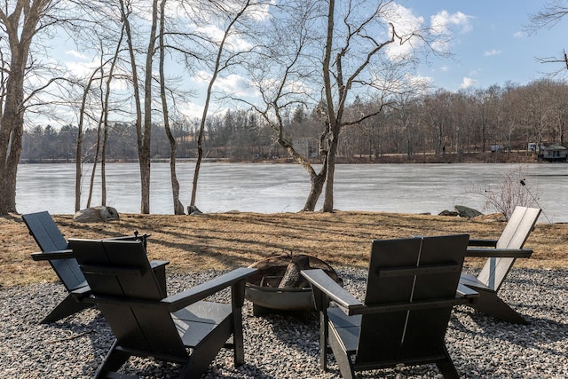 exterior space featuring a fire pit, a wooded view, and a water view