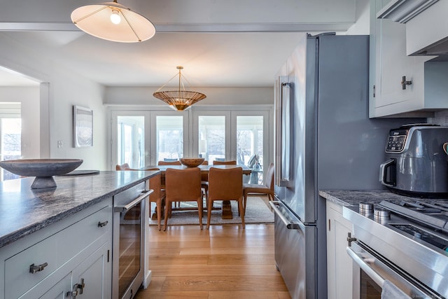 kitchen with dark stone countertops, beverage cooler, french doors, and light wood-type flooring