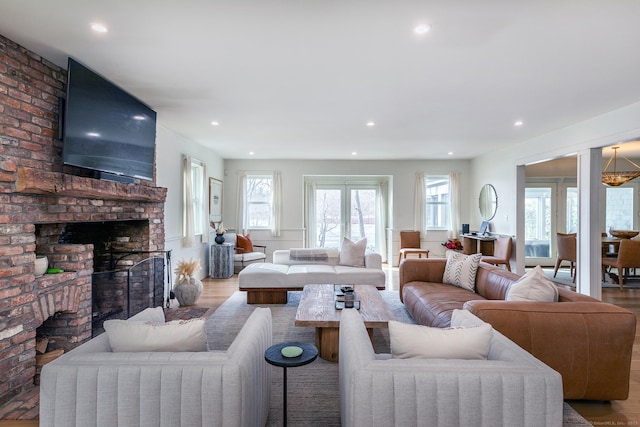living area with a brick fireplace, recessed lighting, and wood finished floors