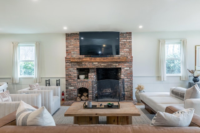 living room with recessed lighting, a wainscoted wall, a brick fireplace, and a decorative wall