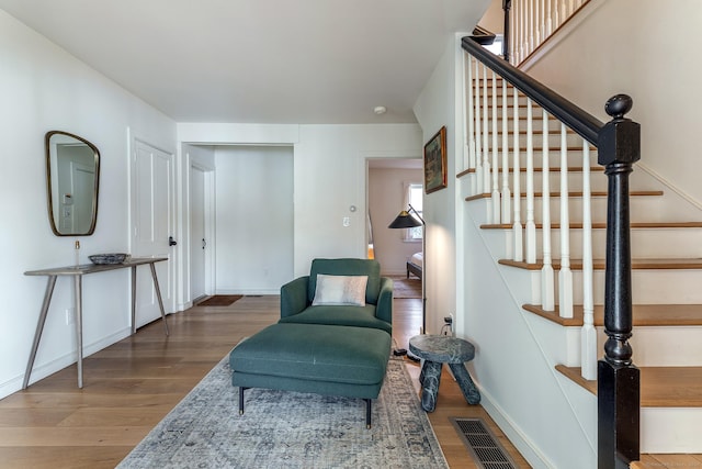 sitting room featuring visible vents, stairway, wood finished floors, and baseboards