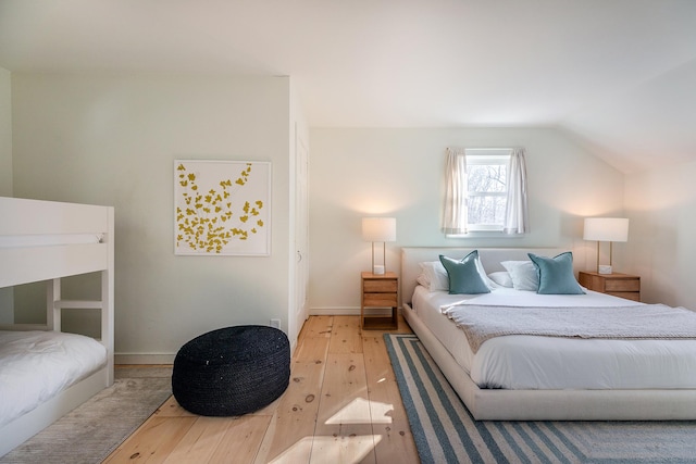 bedroom featuring hardwood / wood-style floors, baseboards, and lofted ceiling