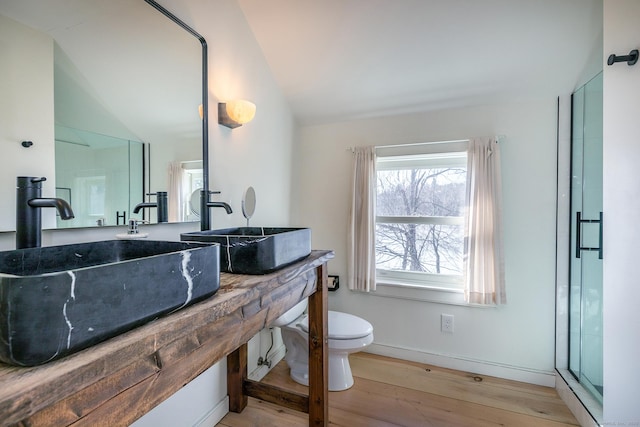 bathroom featuring wood finished floors, a shower with shower door, vaulted ceiling, toilet, and baseboards