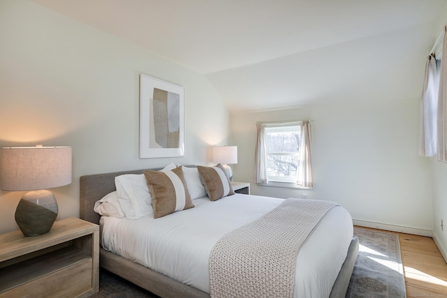 bedroom featuring lofted ceiling, wood finished floors, and baseboards