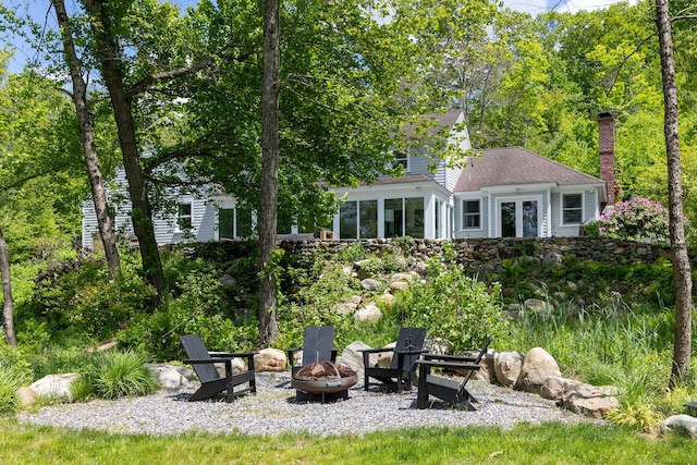 56 Mount Tom Passway Passway, Morris, CT 06763 - back of property with an outdoor fire pit, french doors, a chimney, roof with shingles, and a sunroom