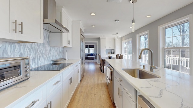 kitchen with backsplash, wall chimney range hood, white cabinetry, black electric cooktop, and a sink