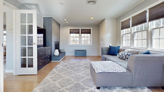 living area featuring visible vents, recessed lighting, a fireplace, and wood finished floors