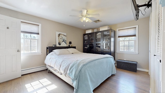 bedroom with visible vents, a ceiling fan, wood finished floors, baseboards, and baseboard heating