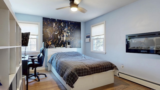 bedroom with light wood finished floors, baseboard heating, and ceiling fan