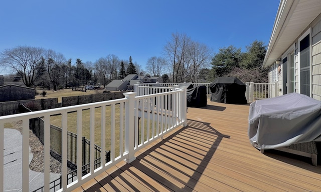 wooden deck with grilling area, a lawn, and fence