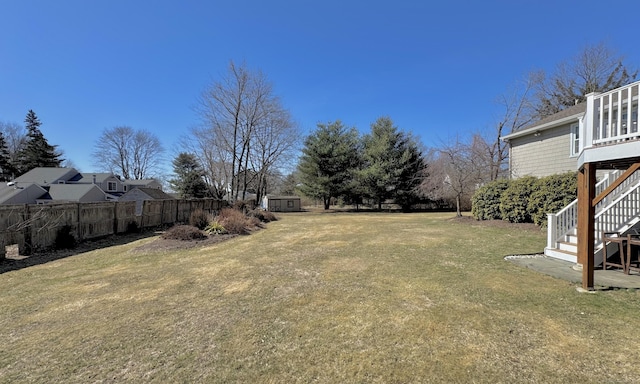 view of yard featuring a shed, stairs, an outdoor structure, and fence