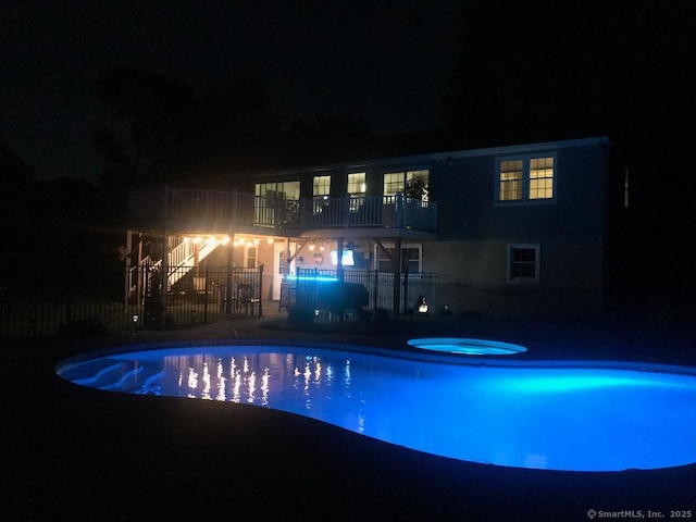 pool at twilight with a fenced in pool, an in ground hot tub, and fence