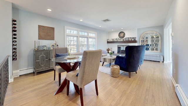 dining space featuring visible vents, recessed lighting, light wood finished floors, a baseboard radiator, and a brick fireplace