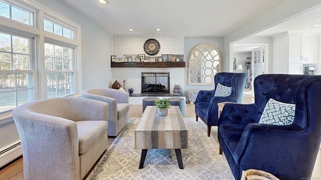 living room with recessed lighting, a brick fireplace, light wood-type flooring, and a baseboard heating unit