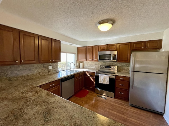 kitchen featuring a sink, tasteful backsplash, dark wood-type flooring, and appliances with stainless steel finishes