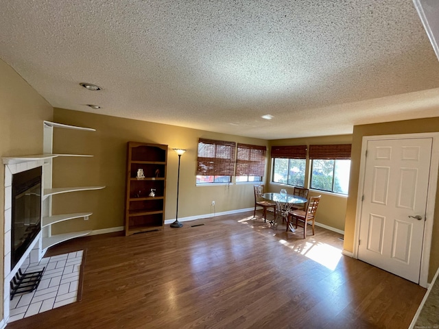 unfurnished dining area featuring baseboards, wood finished floors, and a tiled fireplace