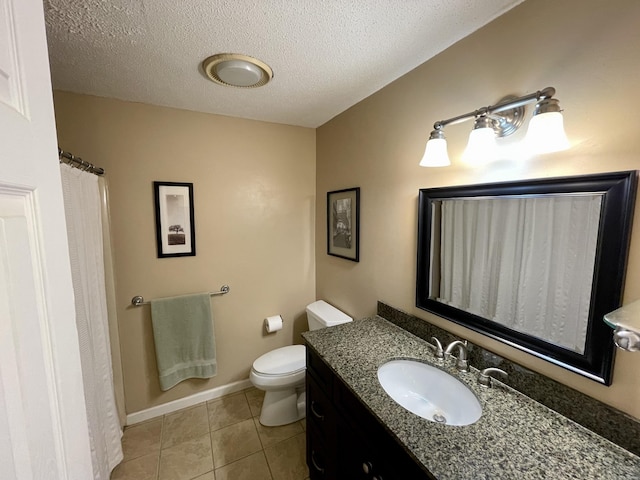 bathroom with baseboards, toilet, vanity, tile patterned floors, and a textured ceiling