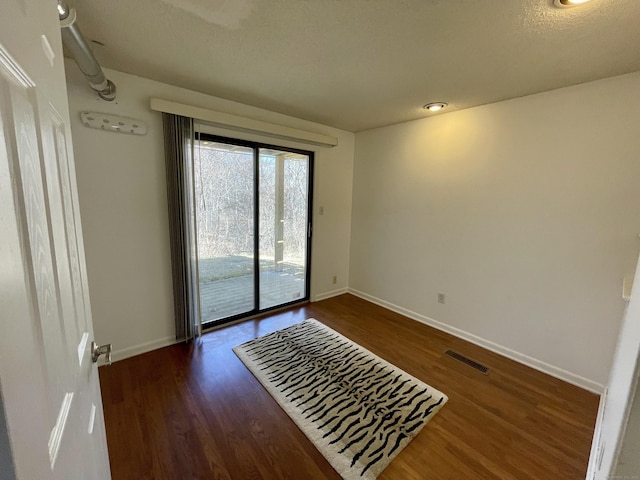 unfurnished room with wood finished floors, visible vents, and baseboards