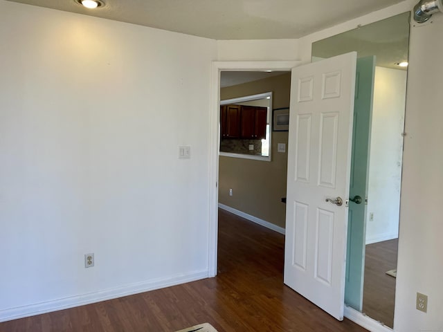 spare room with baseboards and dark wood finished floors