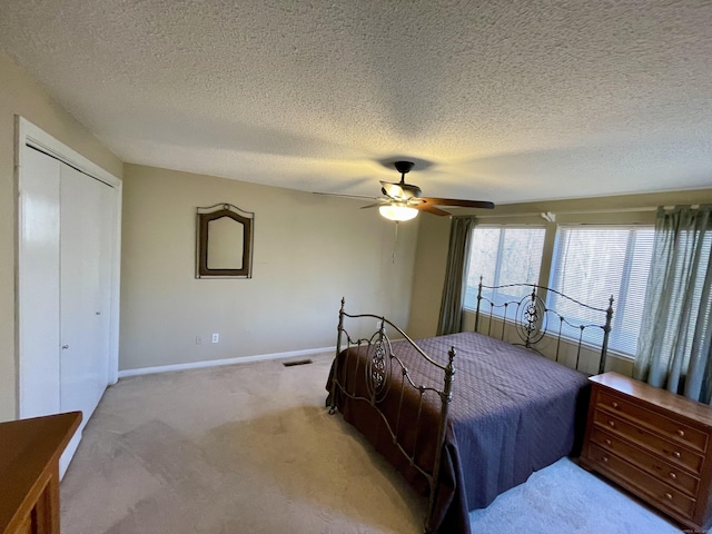 bedroom featuring visible vents, baseboards, light carpet, a closet, and a ceiling fan