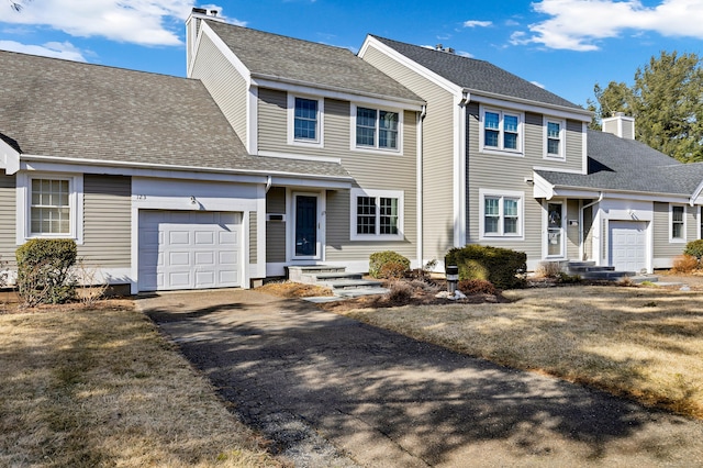 view of front of property featuring a shingled roof, an attached garage, driveway, and a chimney